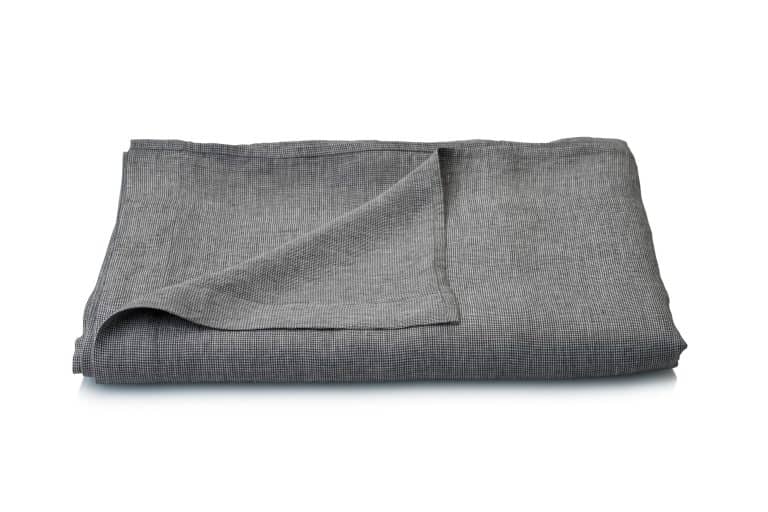 Ein sauber gefalteter Arctica Leinen Bettlaken von Geniksa in Grau mit dezentem Strukturmuster wird auf weißem Hintergrund dargestellt.