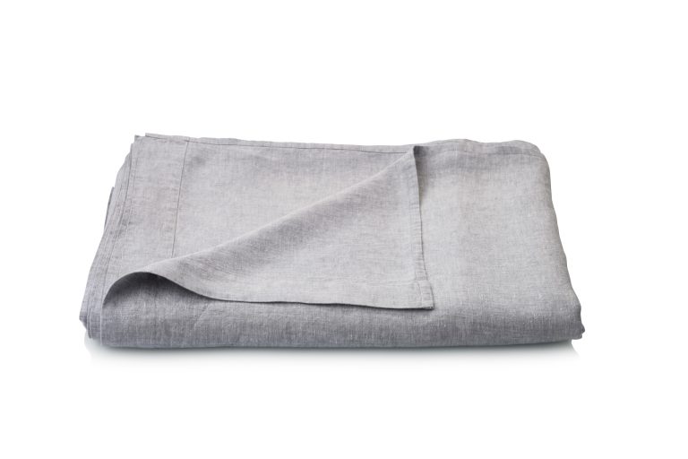 Die hellgrauen Caroline Leinen Bettlaken von Geniksa sind auf weißem Hintergrund ordentlich gefaltet, wobei eine Ecke nach oben zeigt, um die glatte Textur zu zeigen.