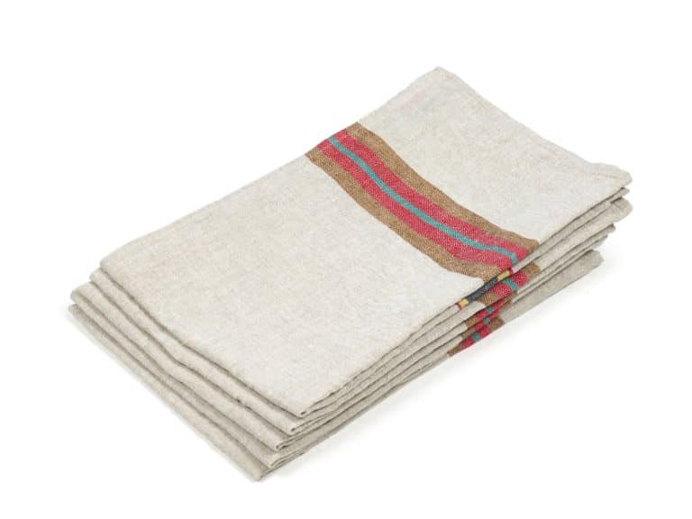 A stack of folded beige linen napkins with a decorative red and brown stripe near the edge, placed on a white background.