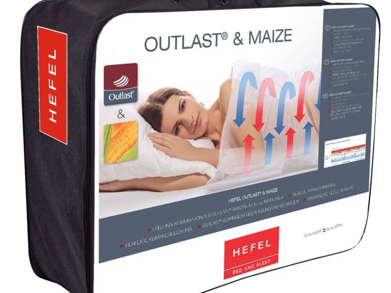 Die Outlast and Maize Ganzjahresdecke von HEFEL kommt in einer überwiegend weißen Verpackung mit roten und blauen Akzenten, die eine Frau auf einem Kissen, Pfeile zur Temperaturkontrolle, Maisbilder und das Outlast-Logo zeigt.
