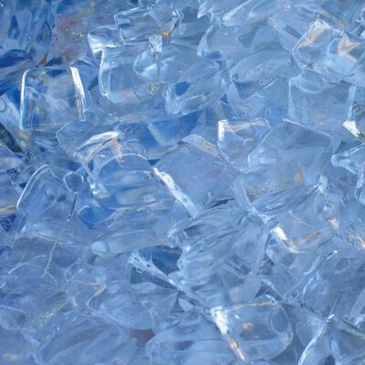 Eine Nahaufnahme vieler klarer Eiswürfel, die übereinander gestapelt sind und eine kühle, transparente Textur mit blauen und weißen Reflexen erzeugen.
