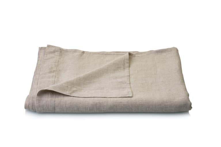 A neatly folded beige linen bed sheet against a plain white background.