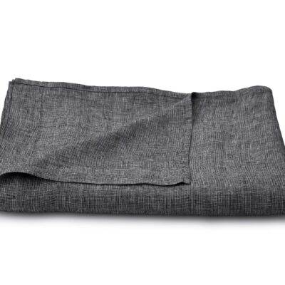 A neatly folded dark grey linen fabric on a white surface, with one corner slightly raised to reveal the texture and weave of the fabric.