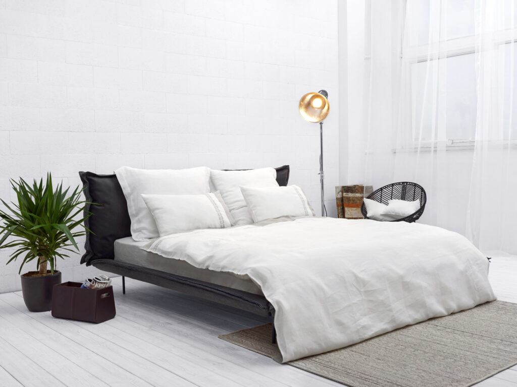 Ein Bett mit weißen Laken und Kissen in einem Zimmer.