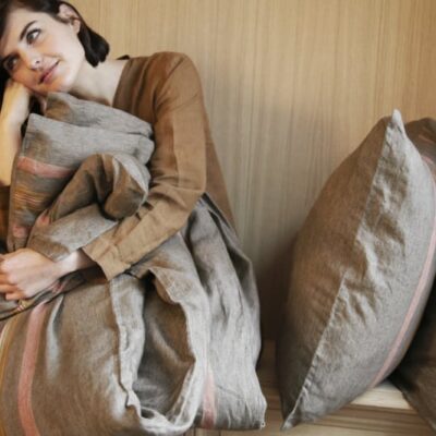 Eine Frau, die auf einem Bett sitzt und eine Decke über dem Kopf hat.