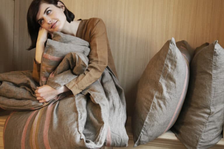 A woman sitting on a bed with a blanket over her head.