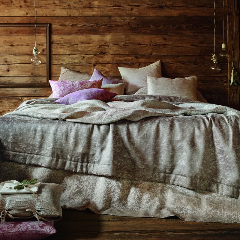 A bed with a wooden headboard and cushions.