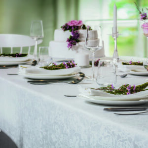 Ein Tisch ist mit weißen Tellern und Silberbesteck gedeckt.