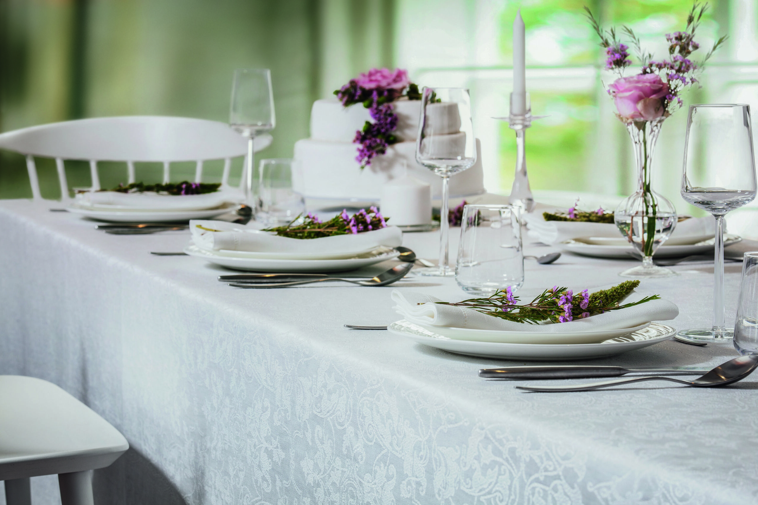 Ein Tisch ist mit weißen Tellern und Silberbesteck gedeckt.