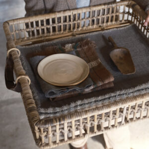 Eine Person, die einen Korbsessel mit einem Teller in der Hand hält.