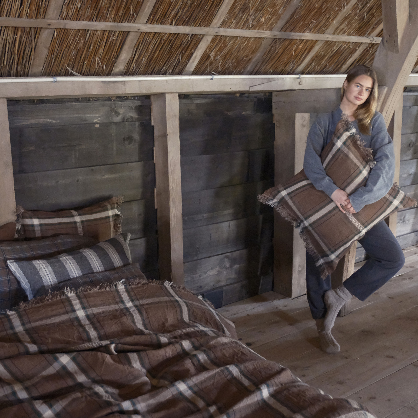 Eine Frau hält zwei Kissen in einem Zimmer.