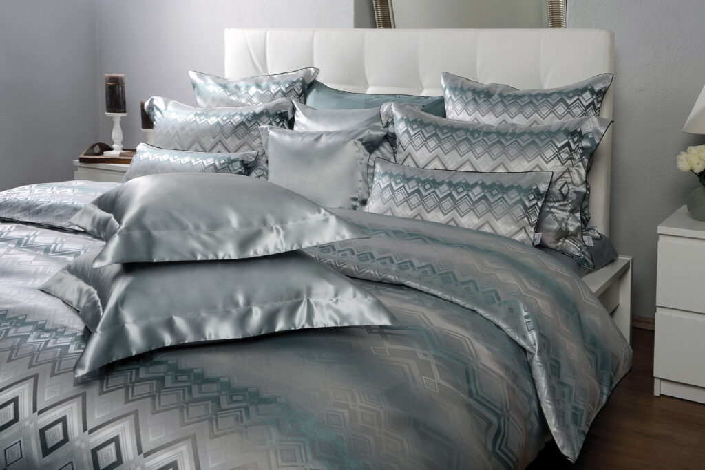 Ein Bett mit einer silbernen Bettdecke und Kissen.