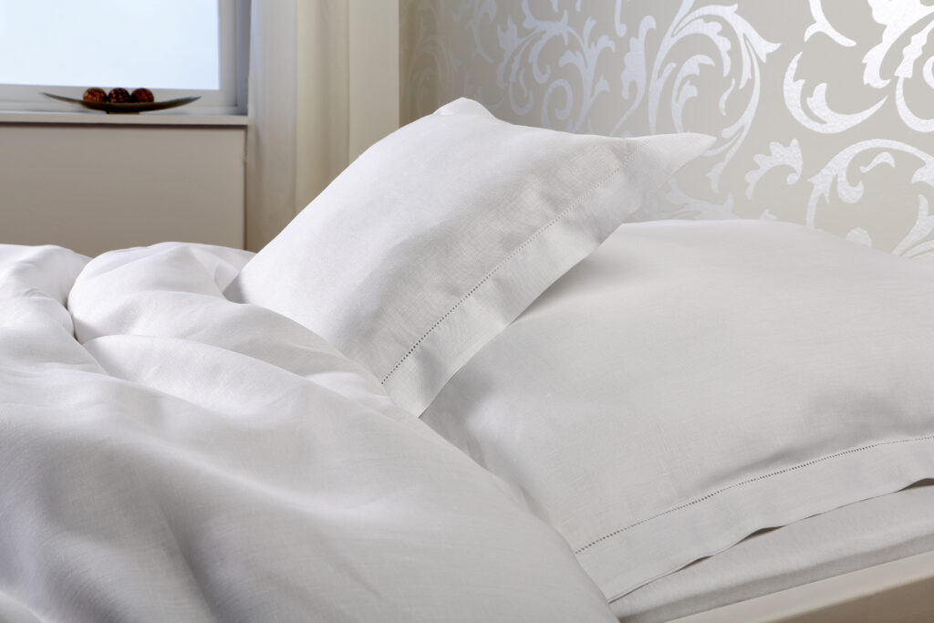 Ein Bett mit einer weißen Bettdecke und Kissen.