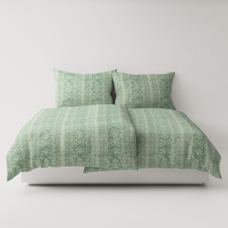 A bed with a green comforter and pillows.