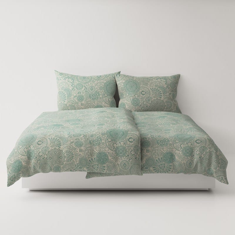 A bed with a green comforter and pillows.