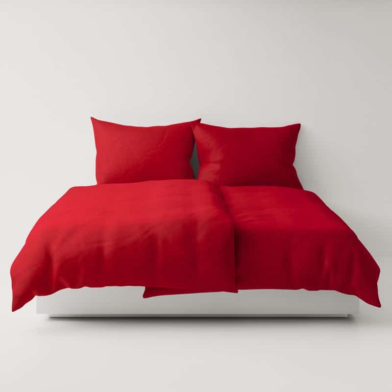A bed with a red comforter and two pillows.