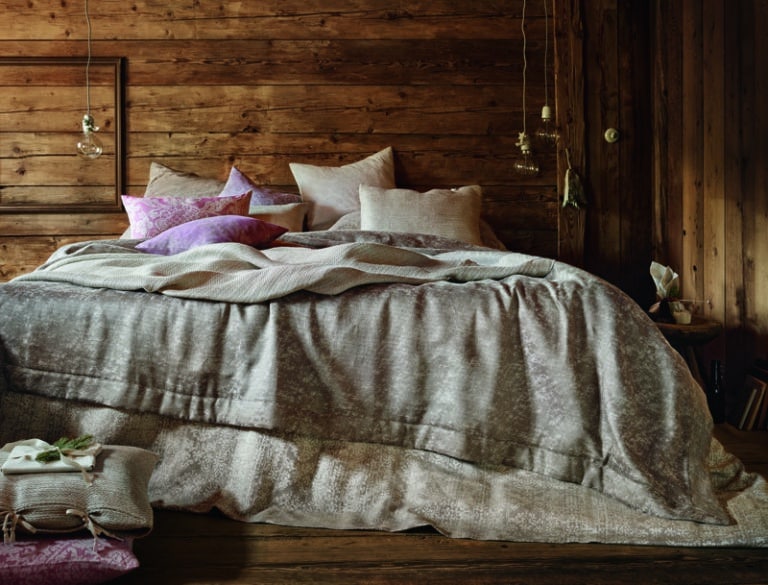 A bed with a wooden headboard and a blanket on top.