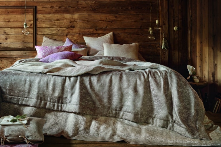 Ein Bett mit einem hölzernen Kopfteil und einer Decke obenauf.