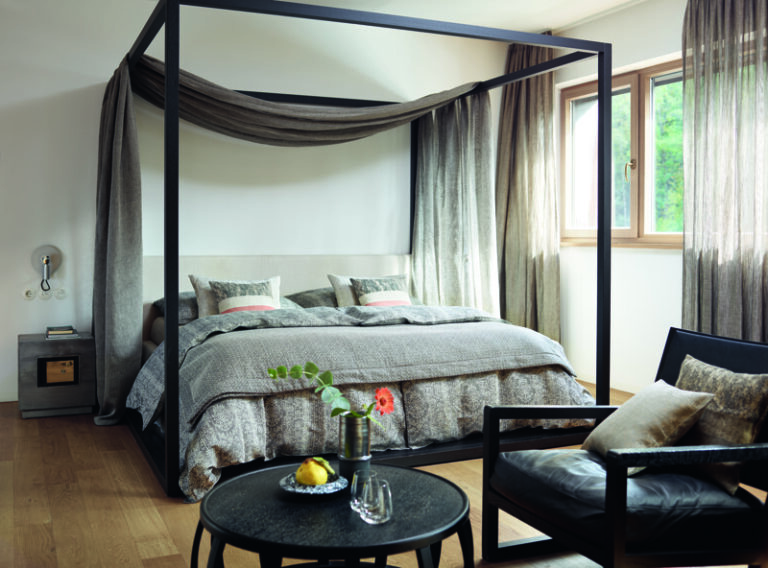 A bedroom with a four-poster bed and a chair.