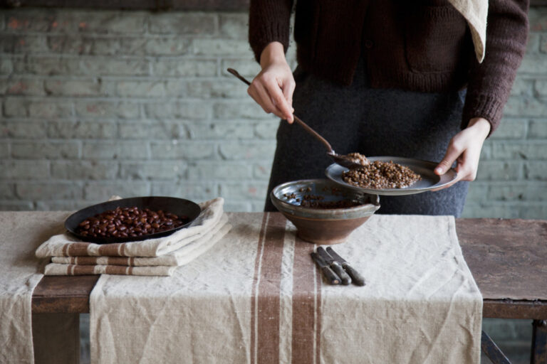 A person standing over a table with a bowl of food.