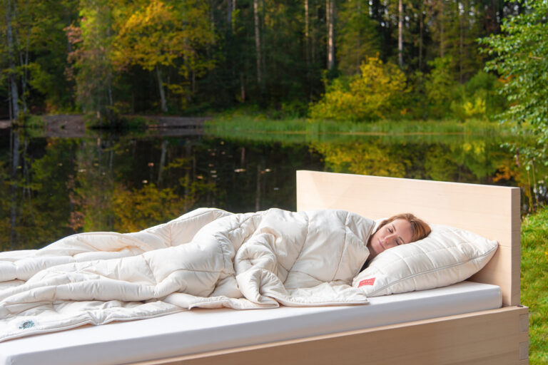 A person lying in a bed with a white blanket.