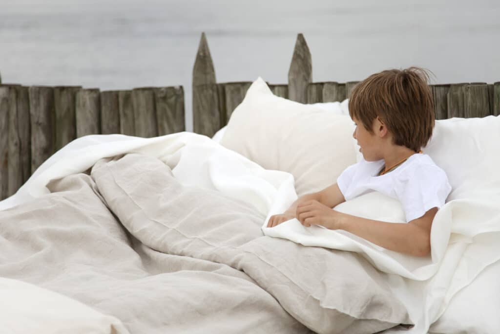 Kleiner Junge liegt warm unter einer Leinendecke im Bett, Bild zu Leinen für Babys und Kleinkinder