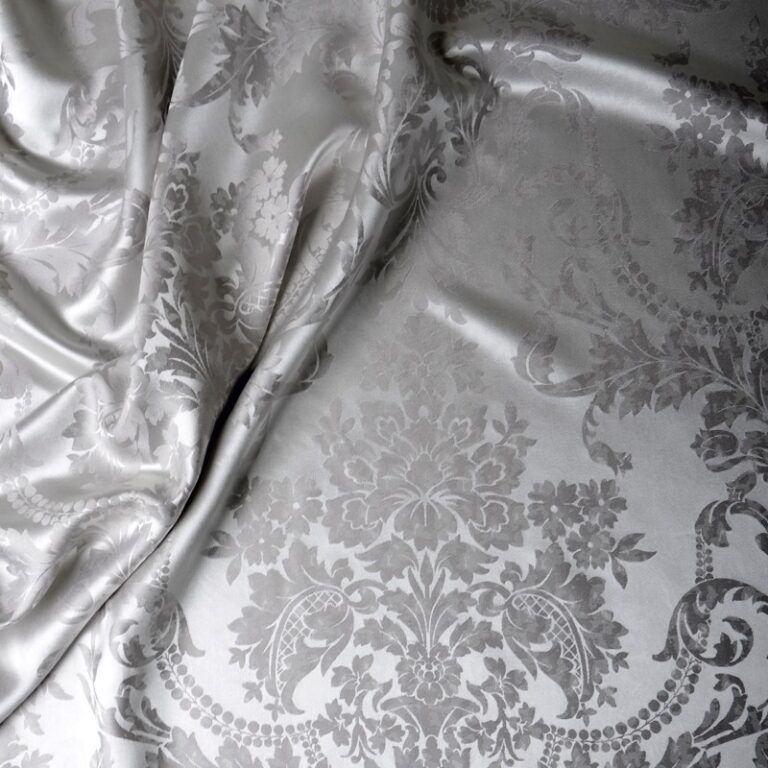 A close-up of a bed with white and grey bedding.