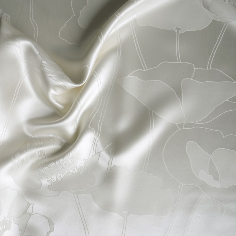 Ein weißes Laken mit einem Blumenmuster darauf.