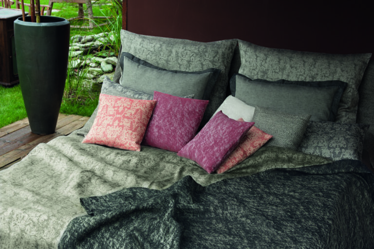 Ein Bett mit einer Decke und Kissen darauf.