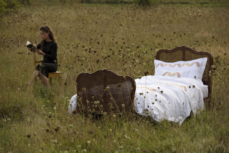 A woman sitting on a bed in a field.