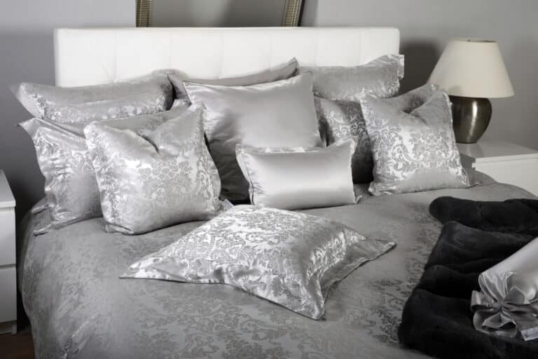 A bed with a pile of pillows on top.