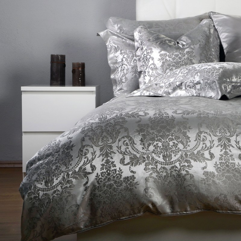 Ein Bett mit einer silbernen Bettdecke und Kissen.