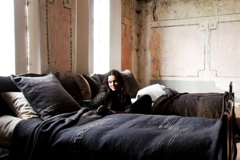 Eine Frau, die auf einem Bett in einem Zimmer sitzt.