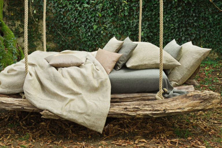A swing bed with a blanket and pillows on it.