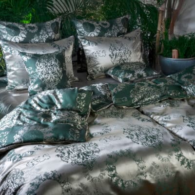 A bed with a green and white duvet.