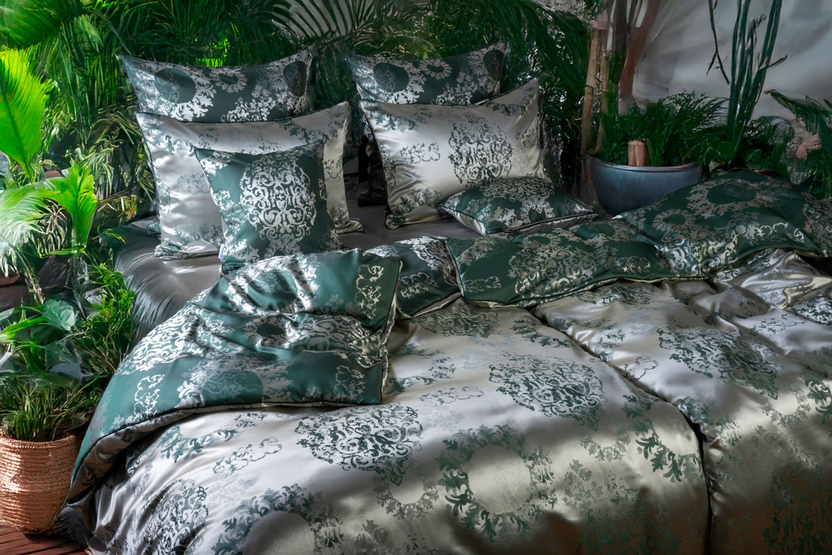 Ein Bett mit einer grün-weißen Bettdecke.