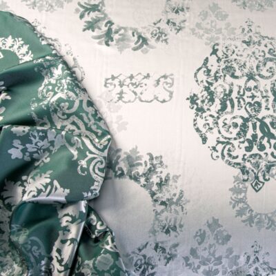 A bed with a green and white duvet on it.