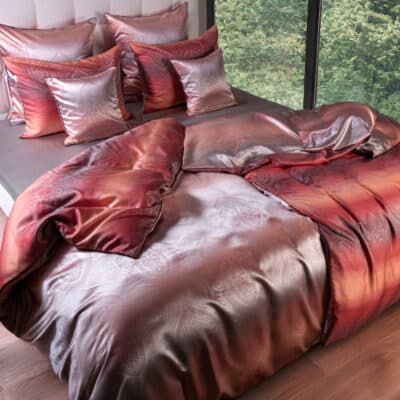 A bed with a red duvet and pillows.