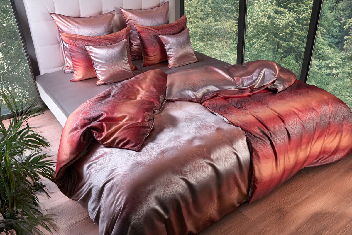 Ein Bett mit einer roten Bettdecke und Kissen.