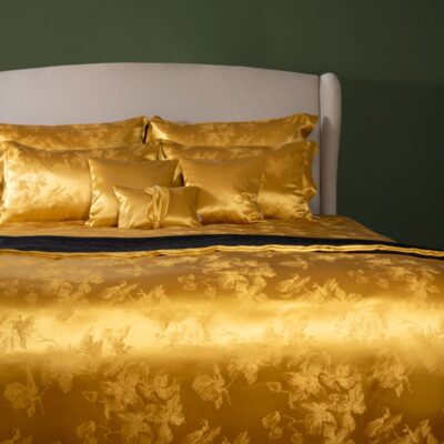 Ein Bett mit einer goldenen Bettdecke und Kissen.