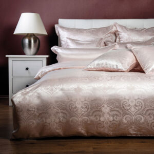 Ein Bett mit einem weißen Kopfteil und einer rosa Bettdecke.