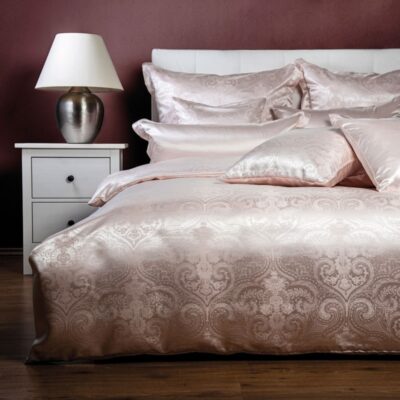 Ein Bett mit einem weißen Kopfteil und einer rosa Bettdecke.