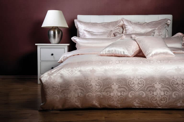 Ein Bett mit einem weißen Kopfteil und einer rosa Bettdecke.