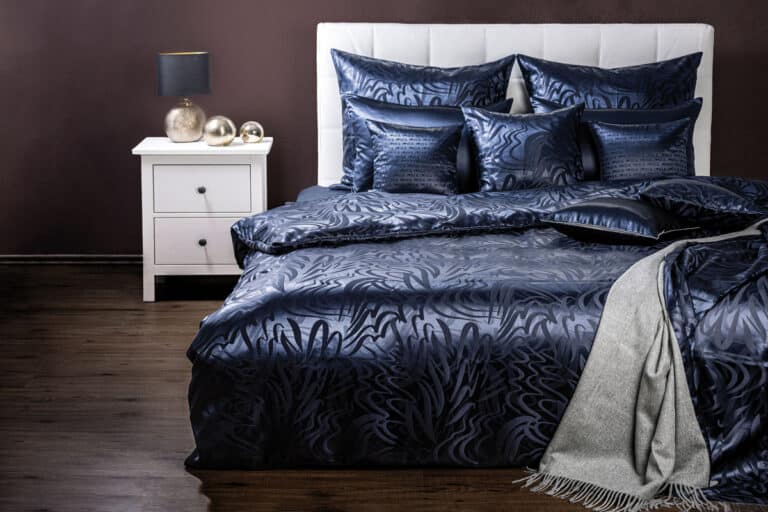A bed with a blue duvet and pillows.