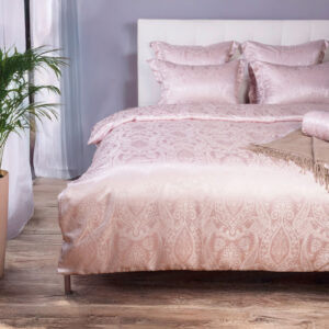 Ein Bett mit rosa Bettdecke und Kissen.