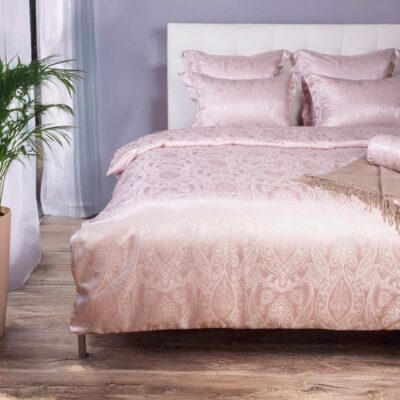 Ein Bett mit rosa Bettdecke und Kissen.