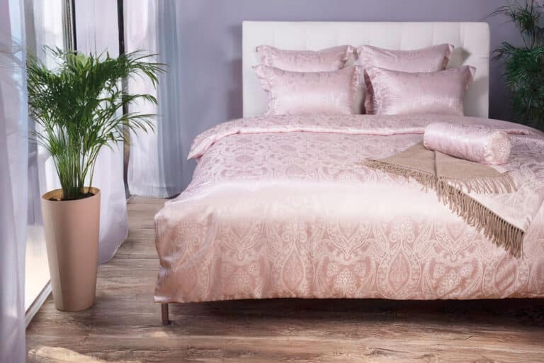 A bed with pink duvet and pillows.