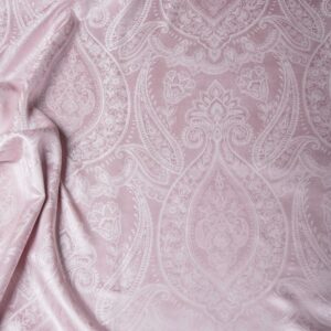 Eine Nahaufnahme eines Bettes mit einer rosa Bettdecke.