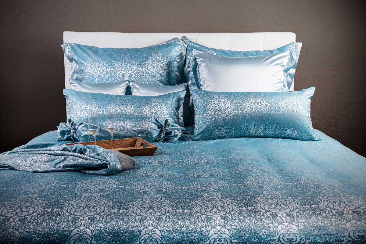 Ein Bett mit einer blauen Bettdecke und Kissen.