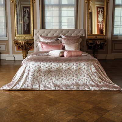A large bed in a bedroom standing next to two mirrors.